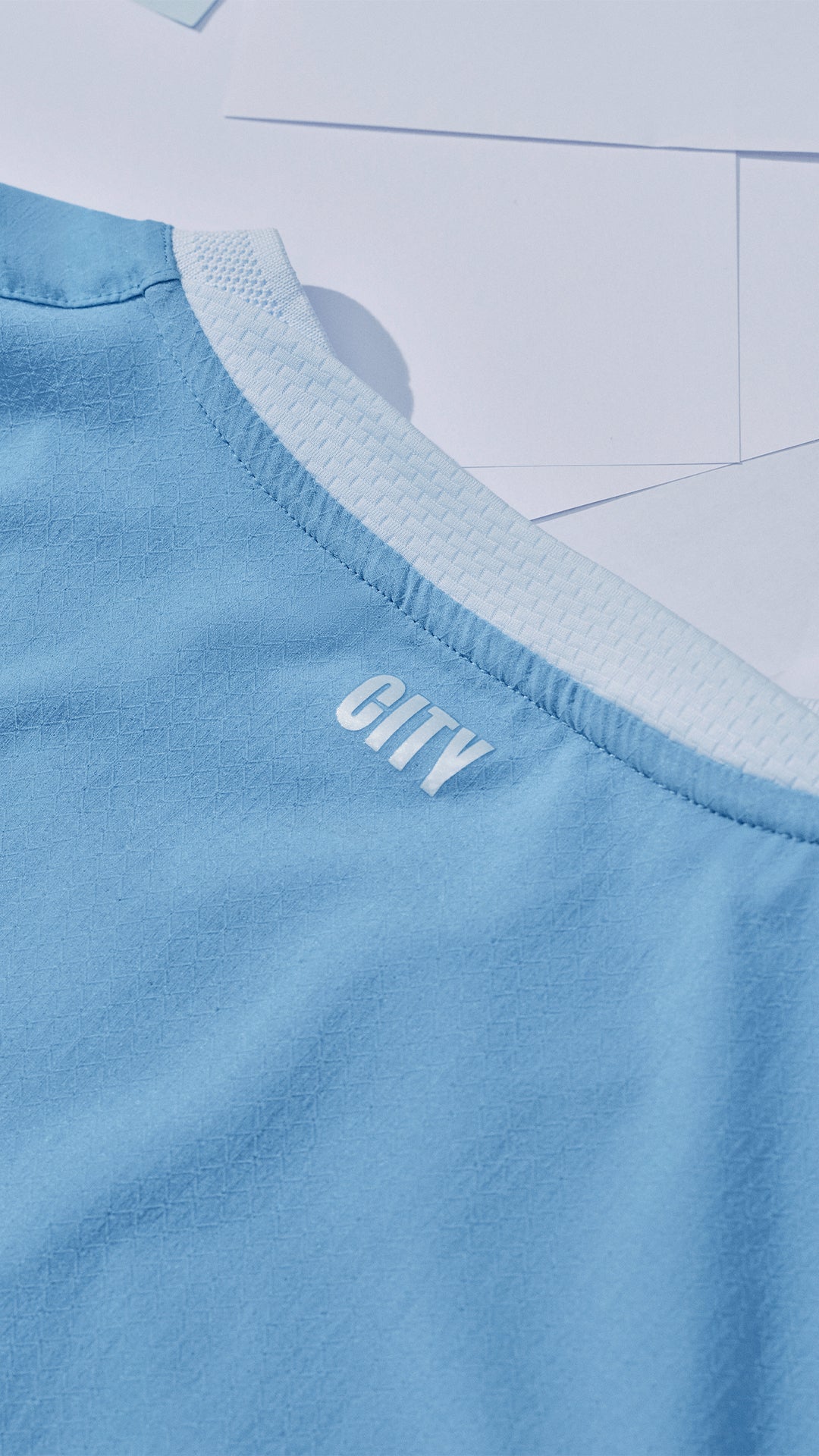 Close-up of a light blue garment with 'CITY' branding on a tiled floor background