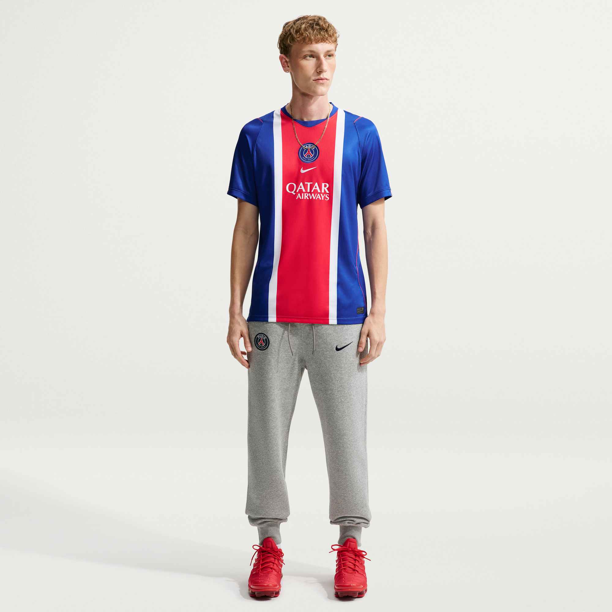 Person wearing a blue and red sports jersey with gray pants on a white background