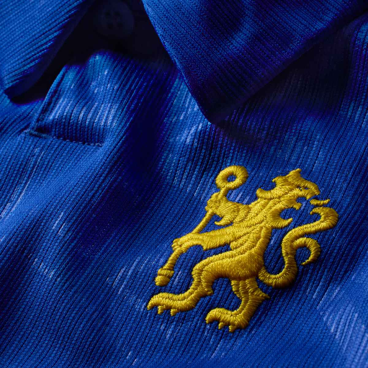 Close-up of a blue fabric with a yellow embroidered lion emblem.